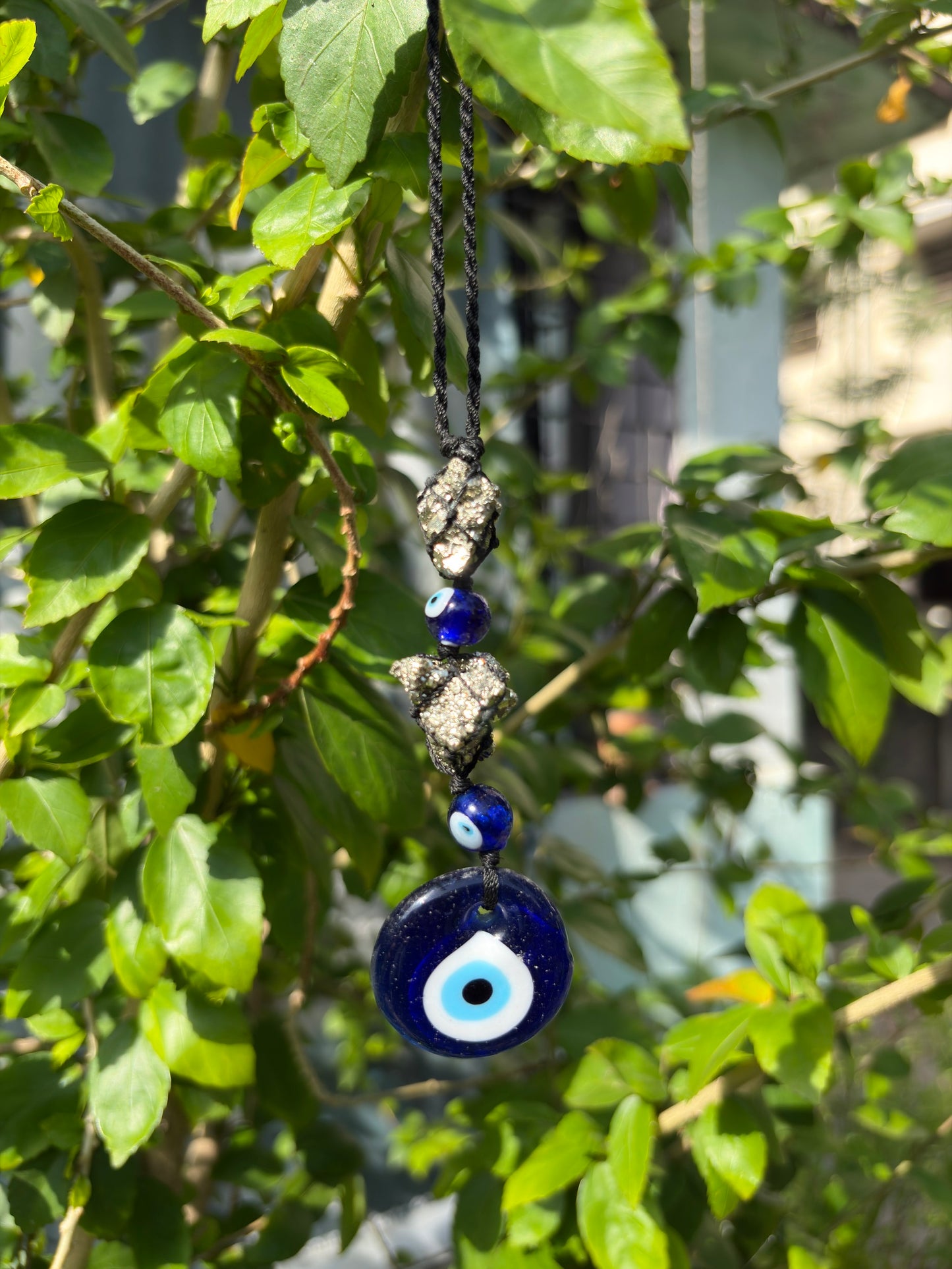 Close up of raw pyrite crystal on evil eye hanger showing natural texture